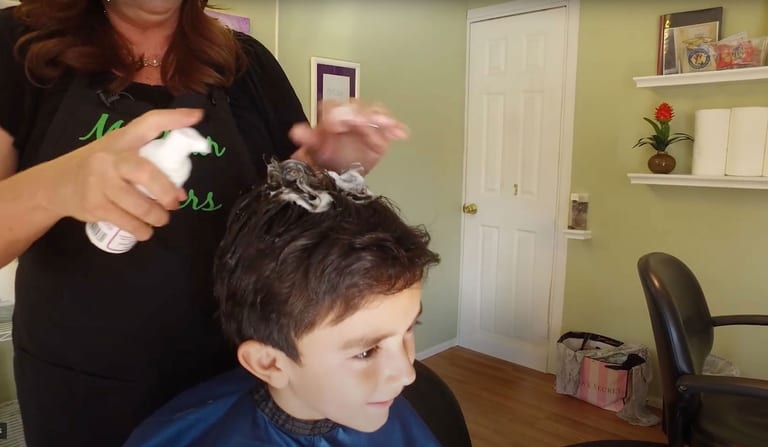 A smiling boy in a treatment chair at a My Hair Helpers lice removal salon